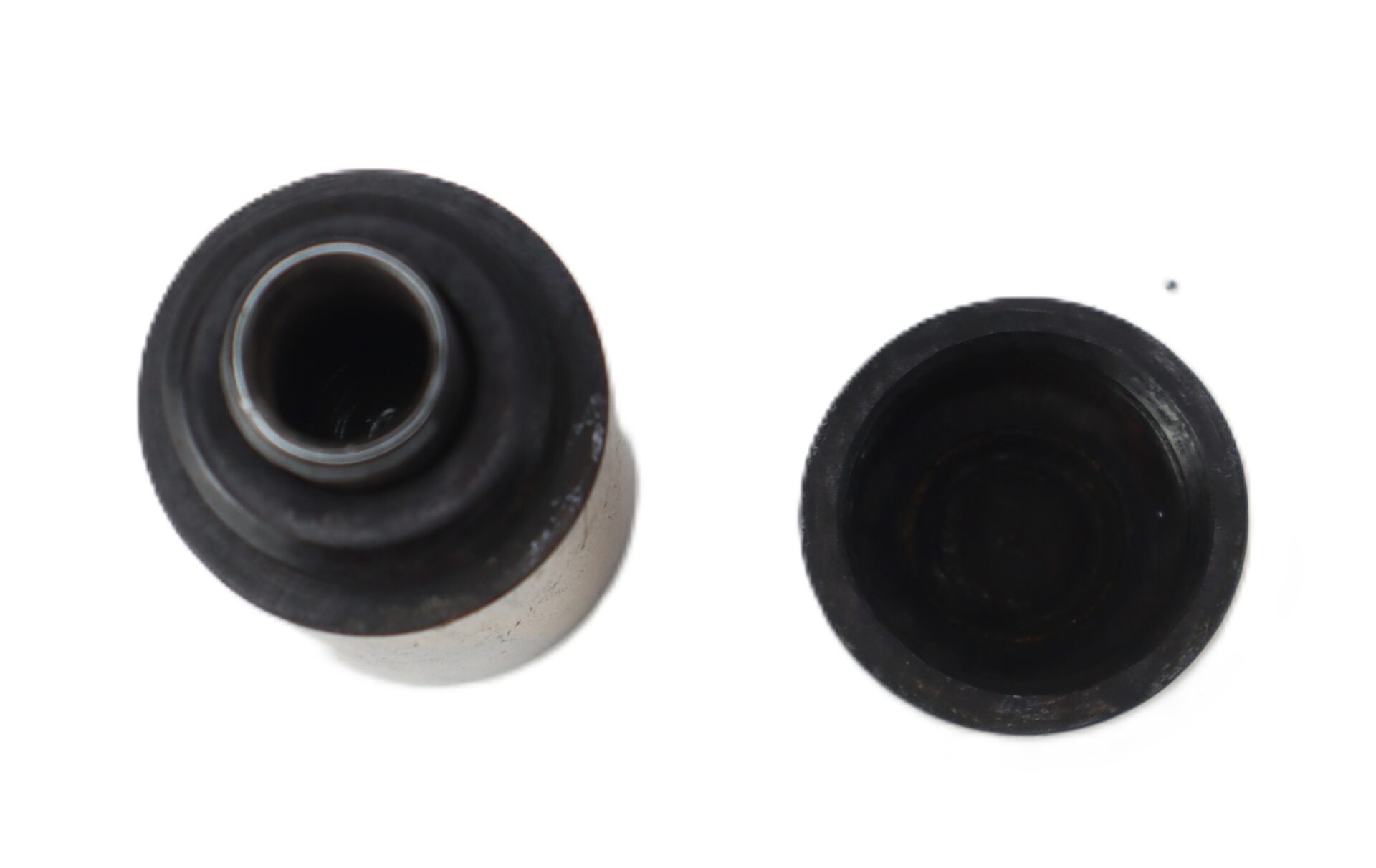 Two black cylindrical objects are shown from above on a white background; one object is upright, while the other is lying on its side.