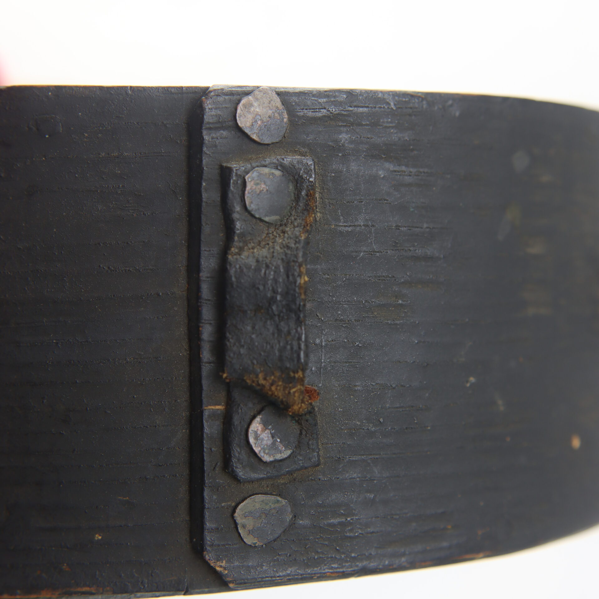 Close-up of the Mexican War Cheesebox Canteen’s black metal band, showing four rivets securing a small bracket to its surface.