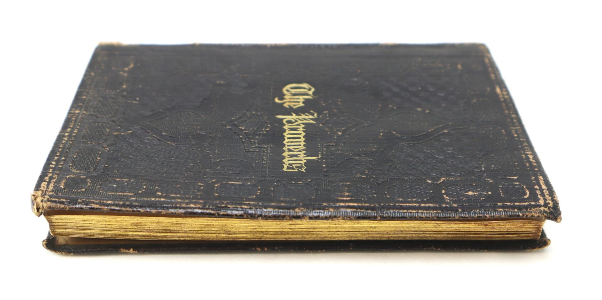 A closed, old black leather-bound book with gold-edged pages and "The Souvenir" written in gold lettering on the cover, photographed against a white background.