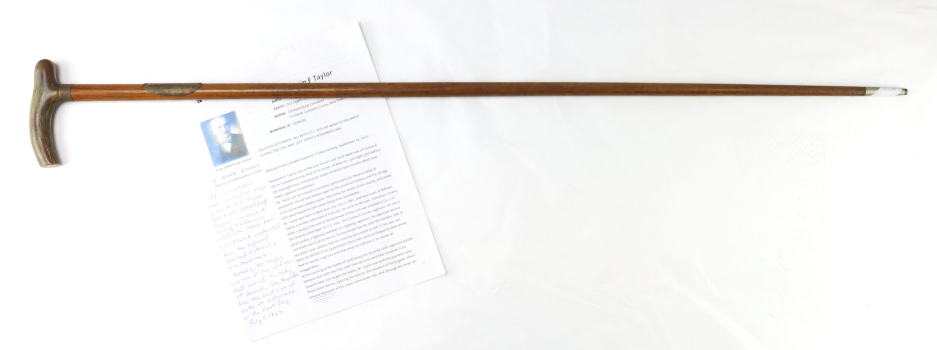 A wooden walking cane with a curved handle is placed diagonally across a printed document on a white surface.