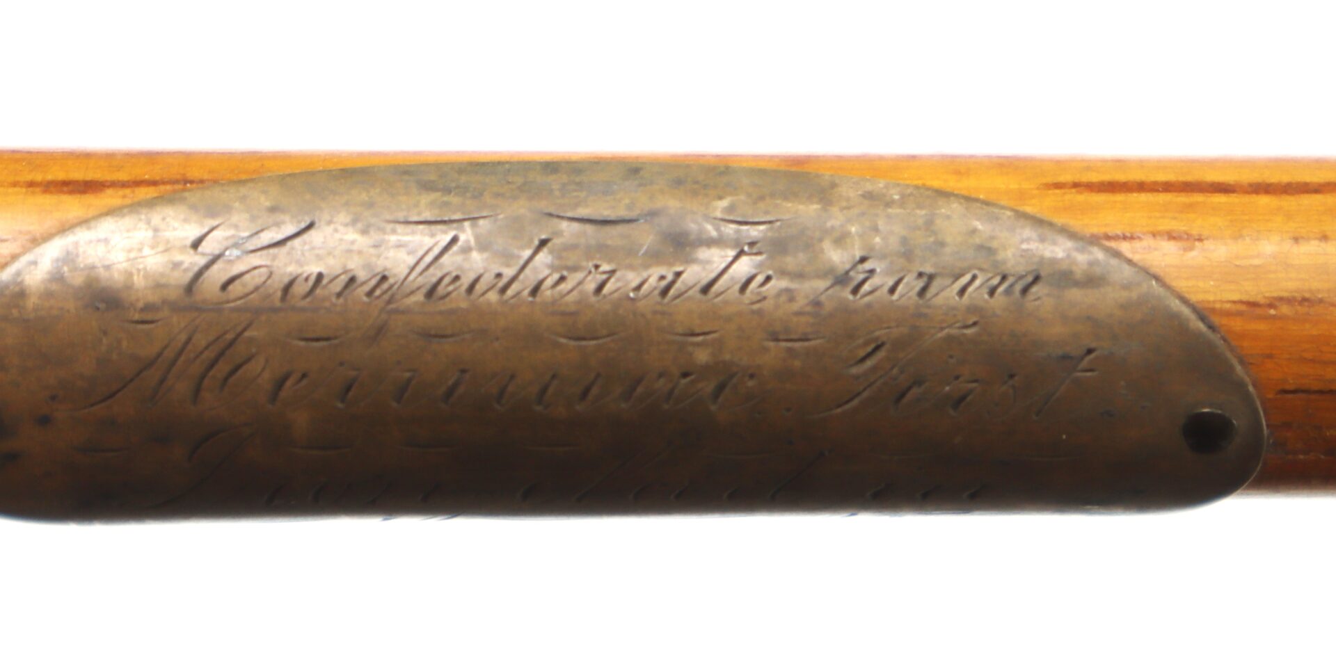 A brass plate engraved with the words "Confederate from Merrimac Fort" attached to a wooden surface.
