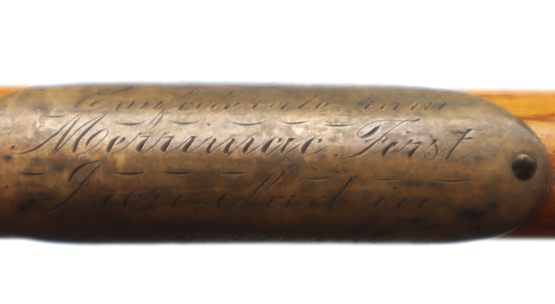 Close-up of an engraved brass plate reading "Confederate Iron Merrimac First" attached to a wooden object, possibly a historical artifact or tool.