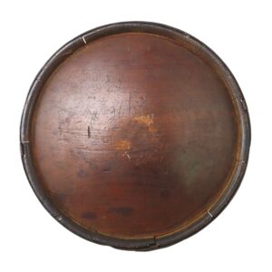 A round, vintage wooden tray with a worn surface and a metal-banded rim, showing scratches and signs of age.