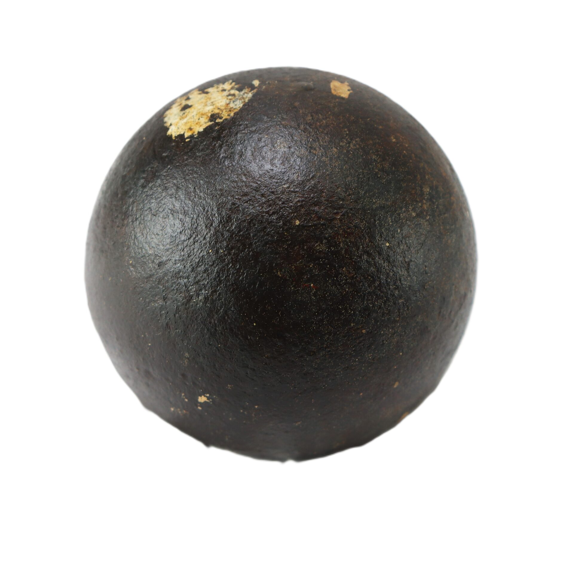 A dark, spherical iron cannonball with a rough, slightly pitted surface and a small area of rust near the top.