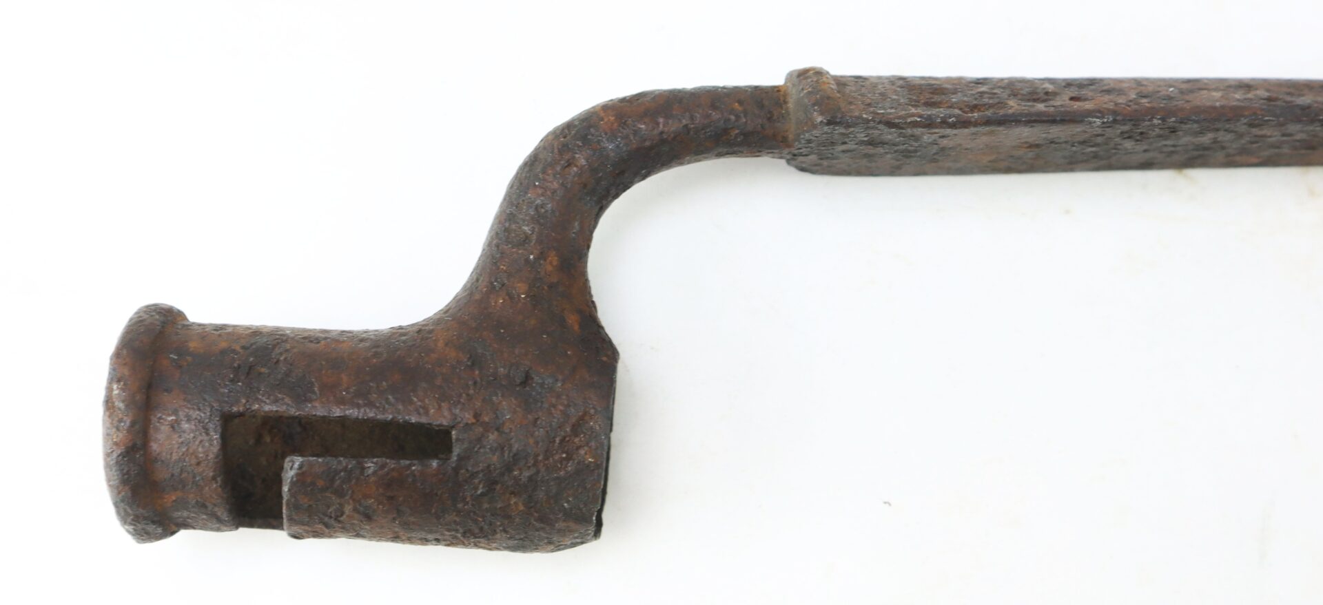 A close-up of a rusty, old metal tool with a curved handle and a hollow, slotted cylindrical end against a white background.
