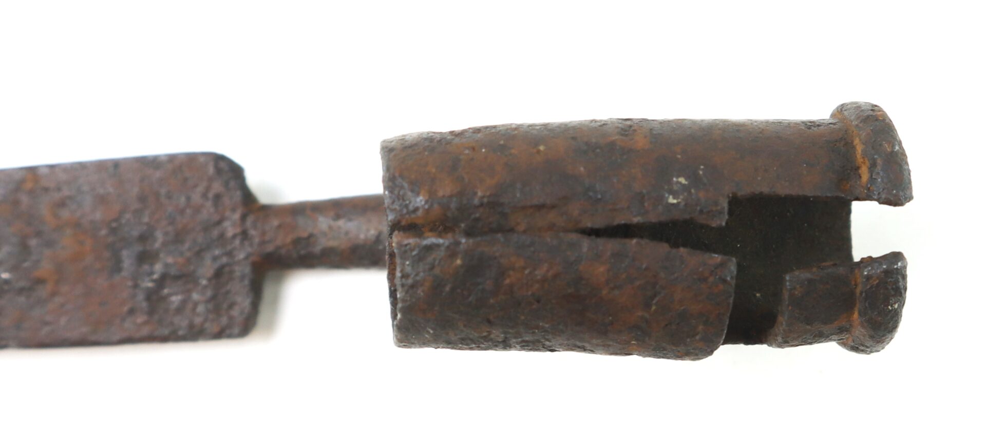 Close-up of a rusted, cylindrical metal object with split, pronged end, and a flat handle, photographed against a white background.