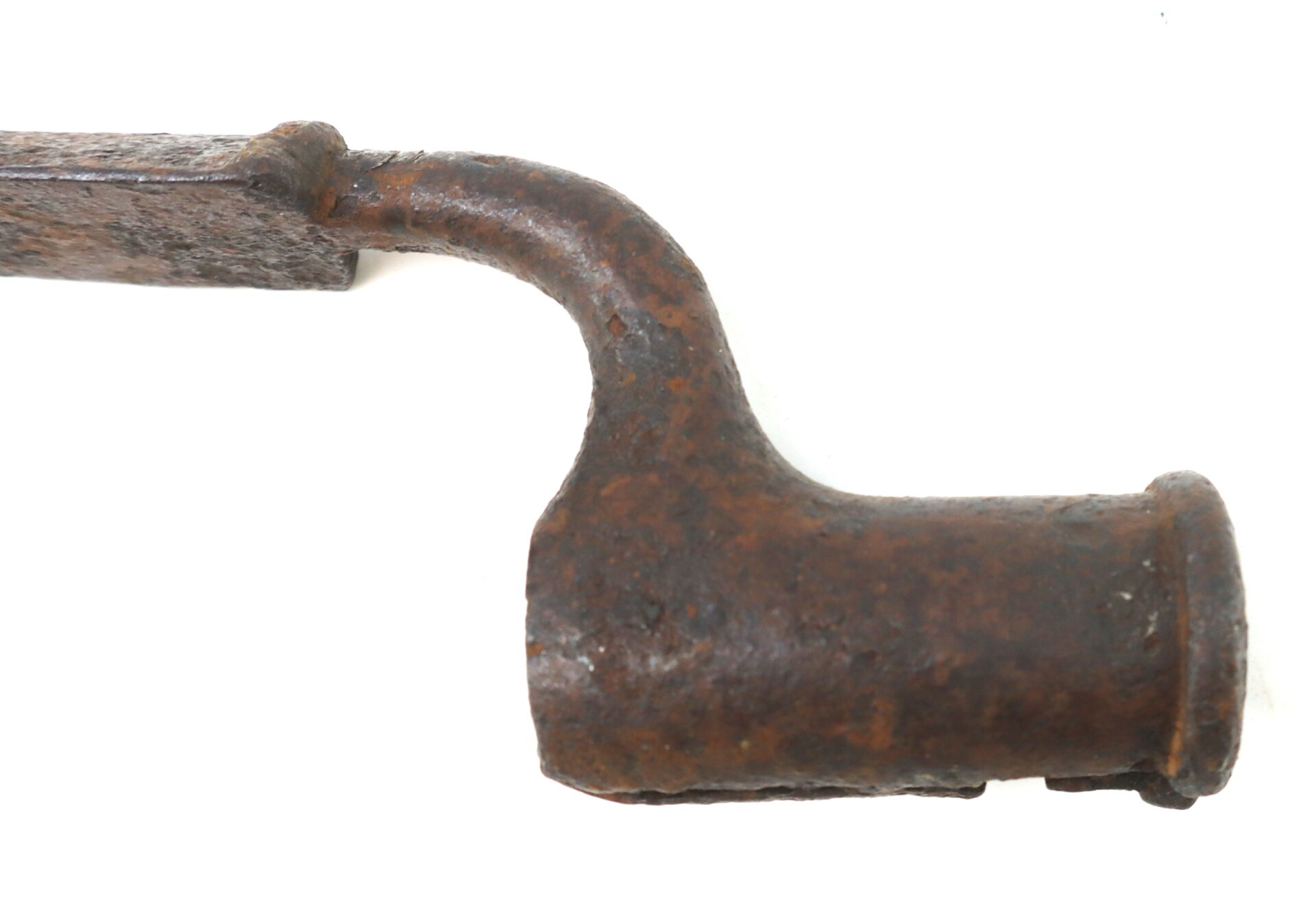 Close-up of a rusted, old metal tool with a cylindrical end and a bent handle against a white background.
