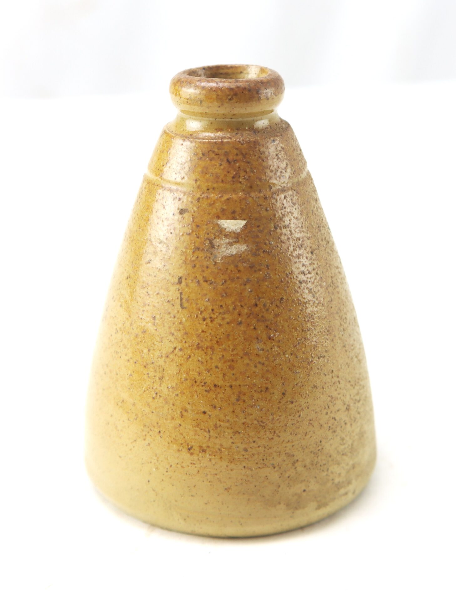 A small, cone-shaped ceramic vessel with a narrow opening, glazed in a speckled light brown color, set against a white background.