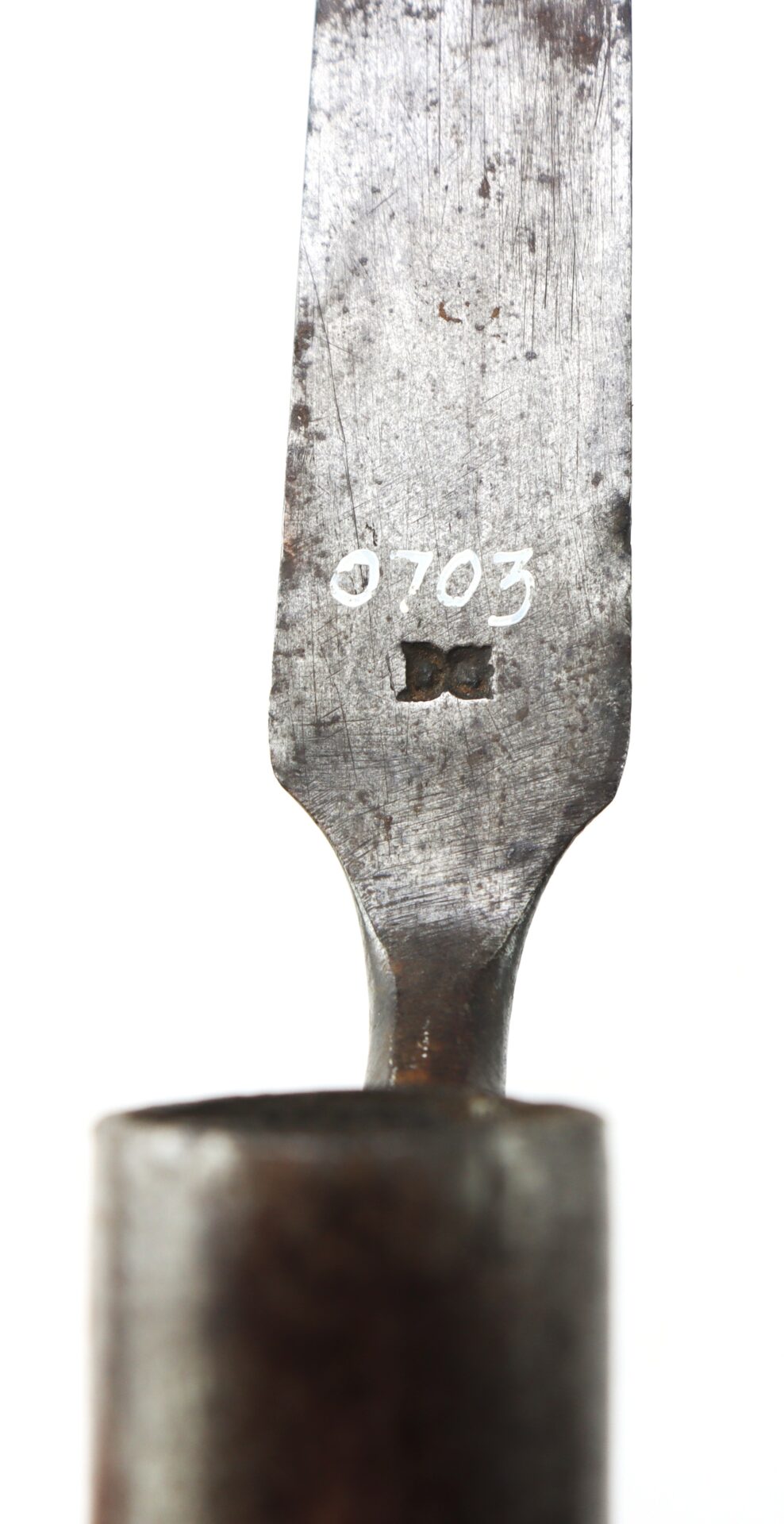 Close-up of a metal tool with the number "0703" and a rectangular mark engraved on its handle.