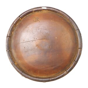 Round, wooden tabletop with visible scratches, a leather-bound edge, and the initials "J.K." engraved on the surface.