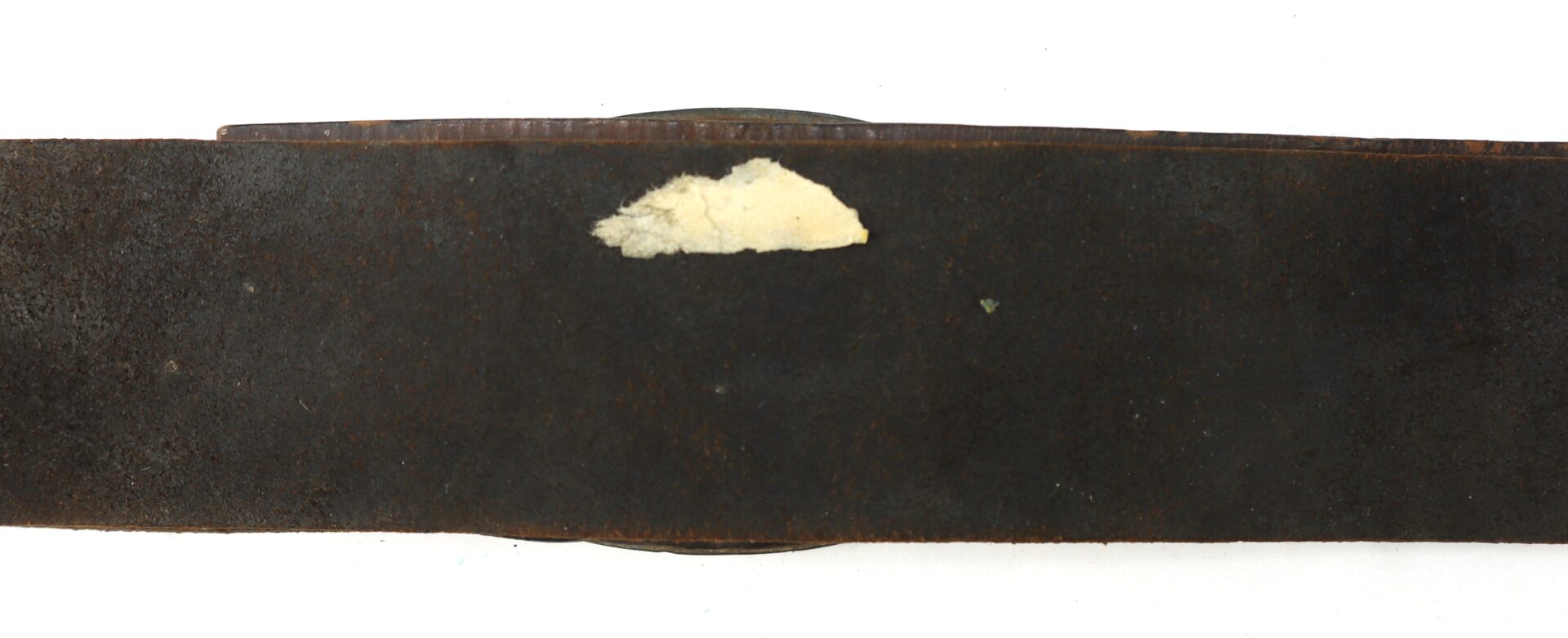 A close-up of a dark, worn leather strap with a small, irregular pale patch near the center.