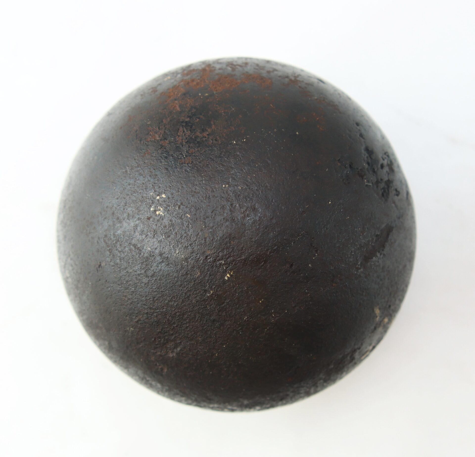 A Confederate Civil War 6-pounder solid shot cannonball, slightly rusty and dark, recovered from Bull Run, displayed on a white background.