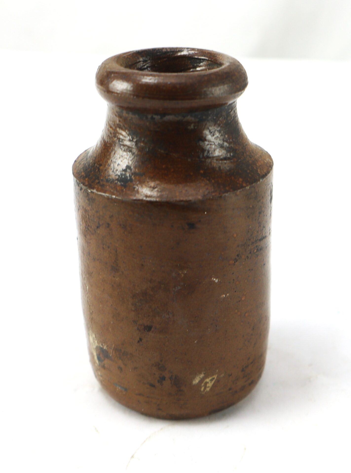 A brown ceramic jar with a short neck and wide lip, set against a plain white background.