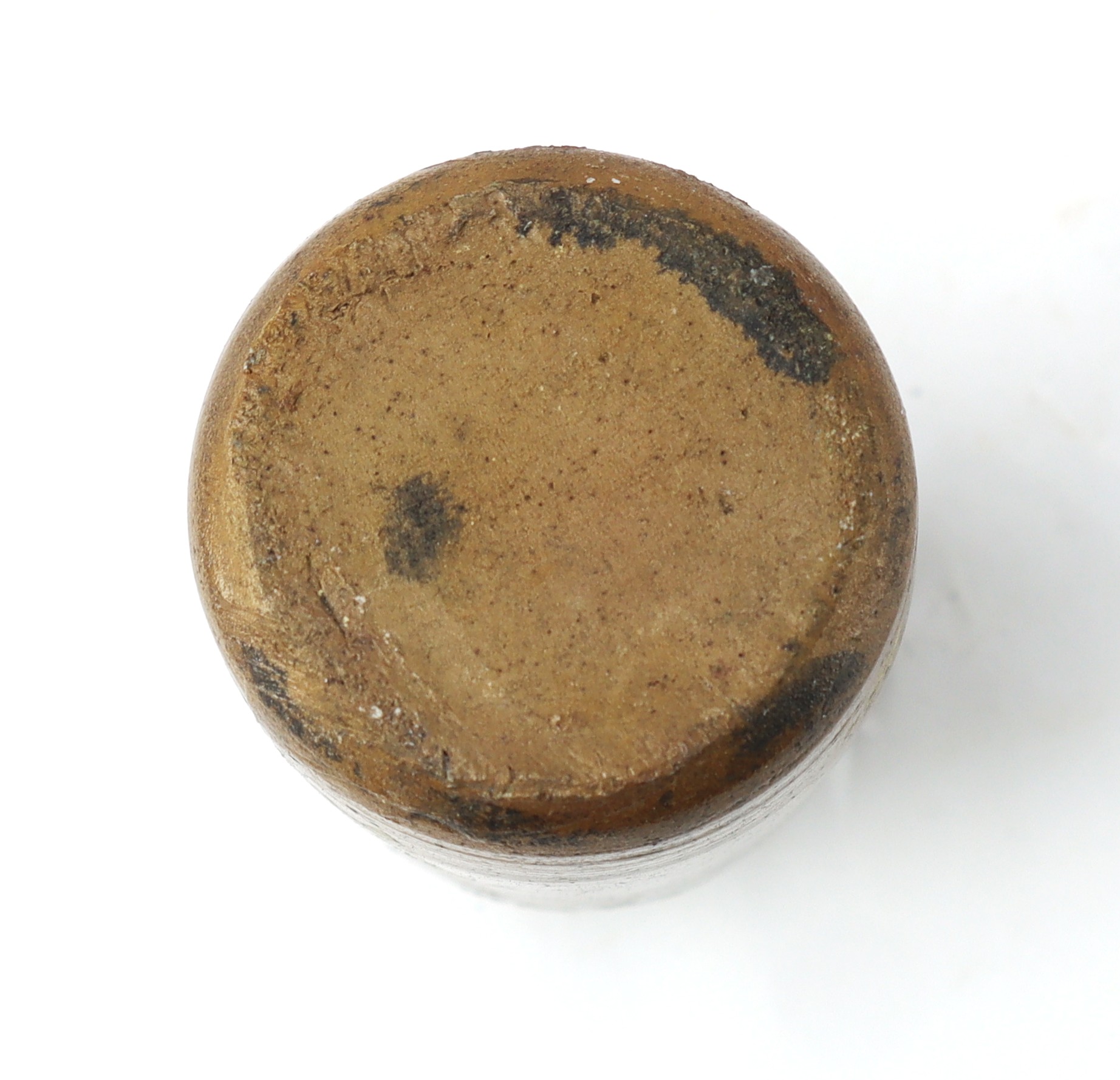 A close-up view of the top of a worn, round, brown cork with dark stains and discoloration.