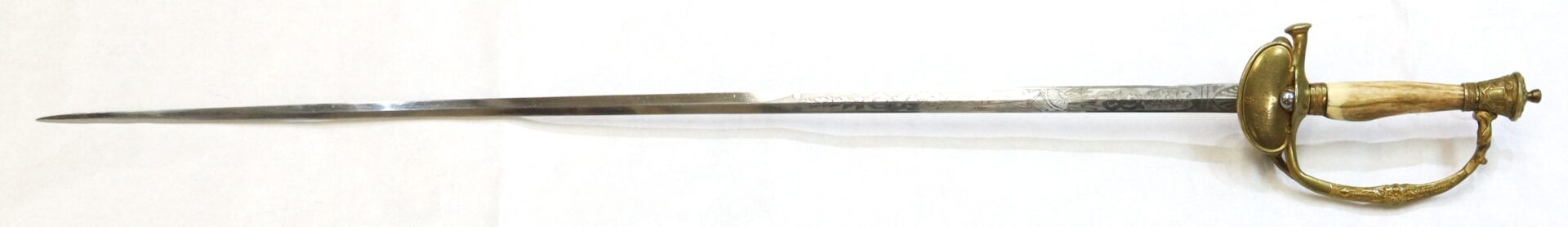 A long, slender sword with an ornate brass guard and a handle resembling wood or bone, displayed on a plain white background.