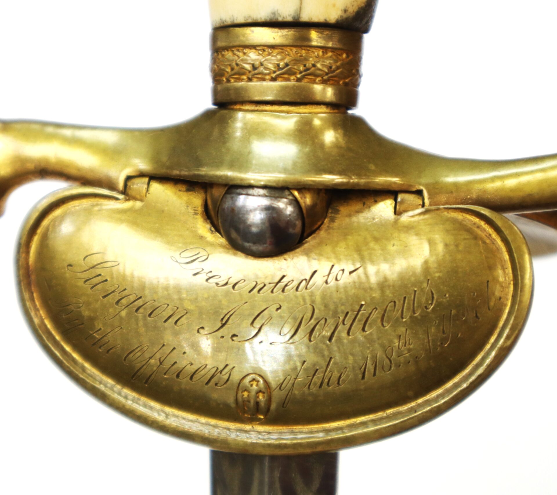 Close-up of a brass sword guard engraved with the inscription, "Presented to Surgeon J. J. Dorticous by the officers of the 118th Regt.