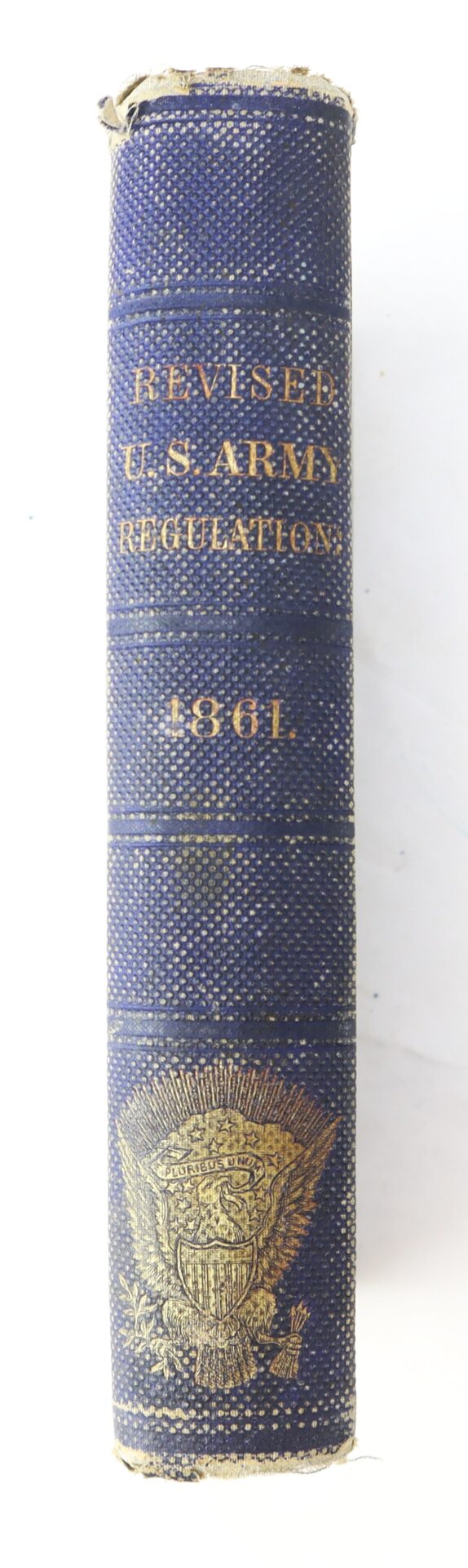 Spine of an old book labeled "Revised U.S. Army Regulations 1861" with a gold embossed emblem at the bottom.