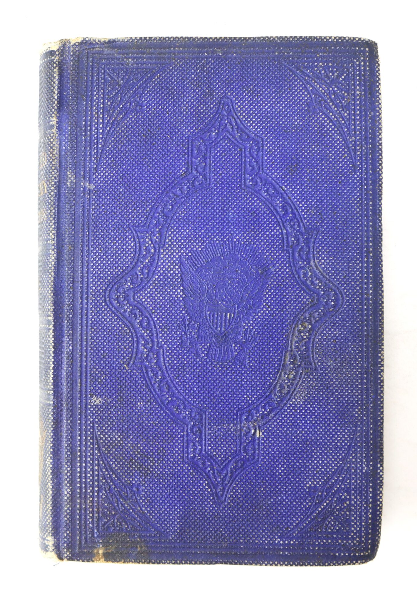 A worn, ornate dark blue book cover with a textured pattern and an embossed emblem in the center.