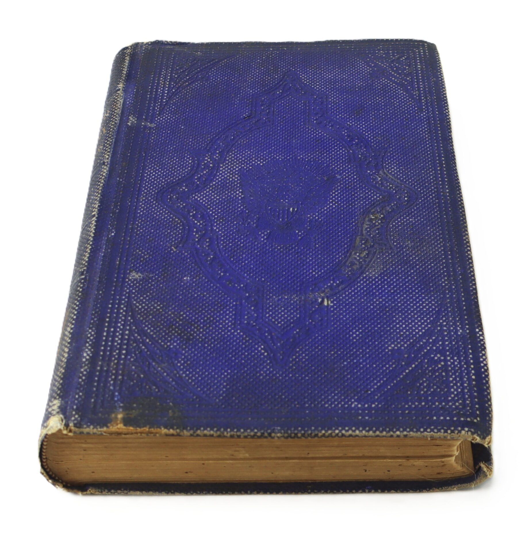 A closed, worn, antique book with a blue textured cover and gold-edged pages, photographed against a white background.