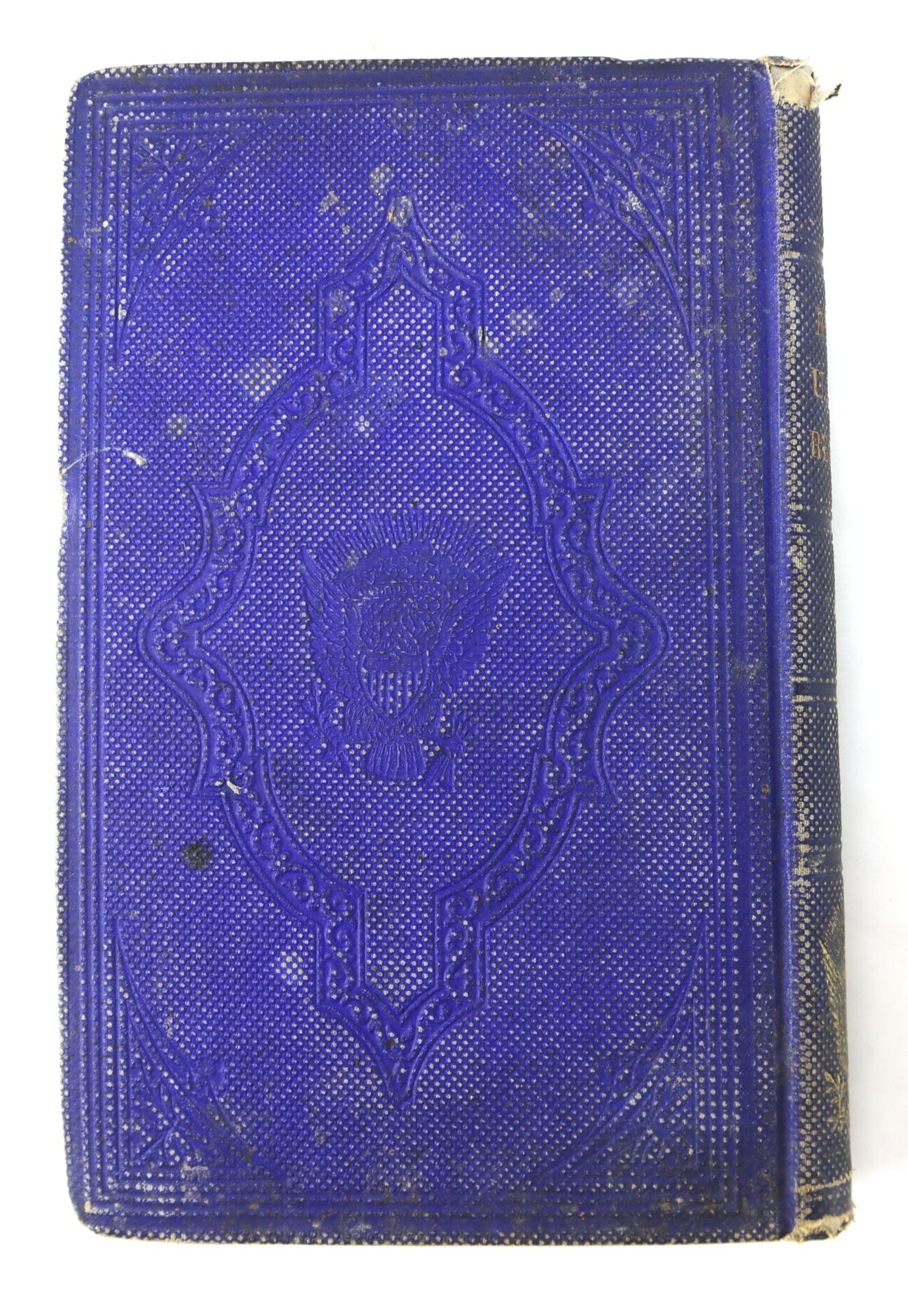 A worn, textured blue book cover with an embossed eagle emblem in the center and decorative borders; the spine shows visible wear.