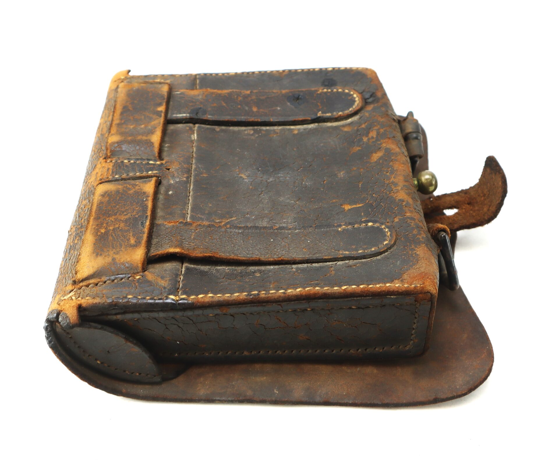 A worn, vintage brown leather satchel with visible scuffs, cracks, and a partially open flap, resting on a white background.