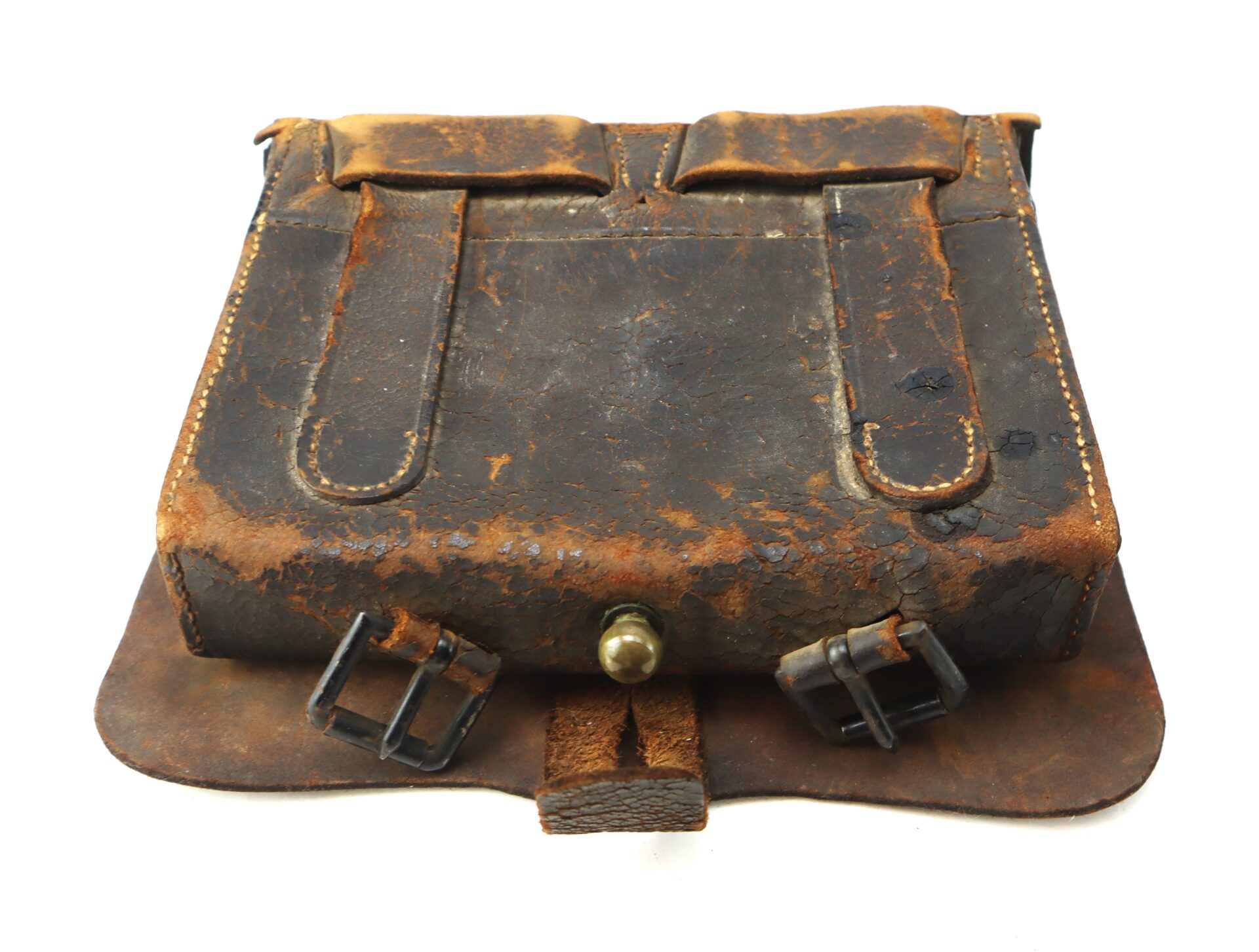 A worn, vintage brown leather satchel with visible scuffs, two front straps, metal buckles, and a brass knob closure.