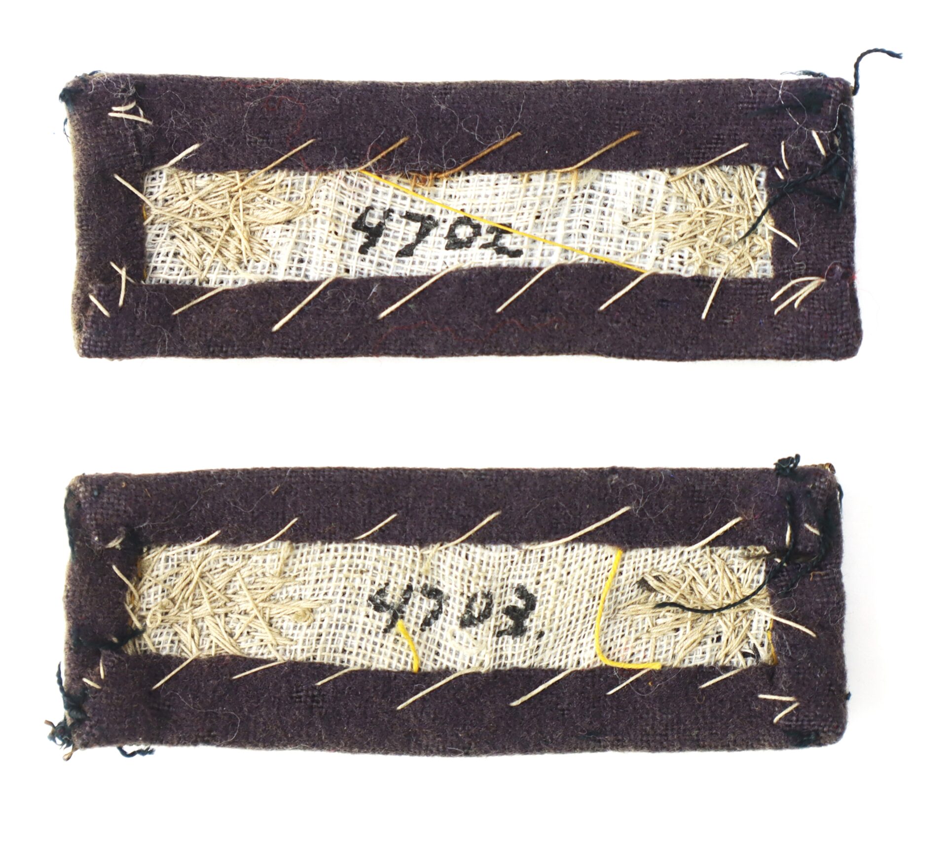 Two rectangular fabric swatches with rough stitching and exposed straw, each displaying handwritten numbers "4702" and "4703" on visible patches of cloth.