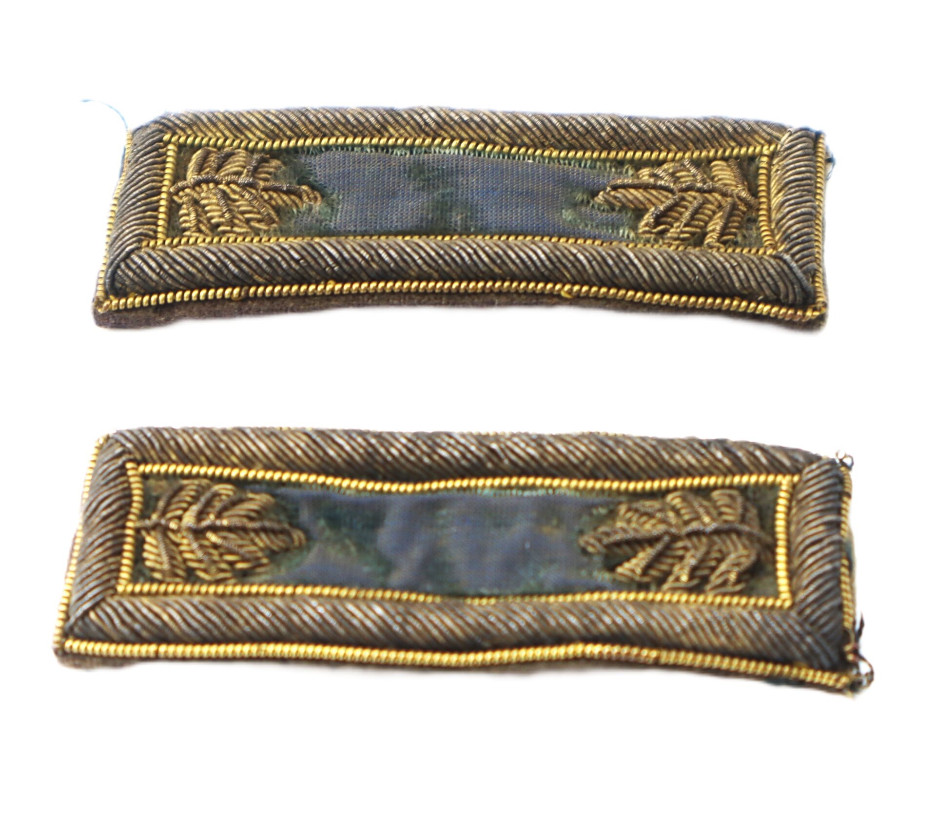 Two rectangular military rank insignia featuring gold embroidered oak leaves and borders on a faded green background.