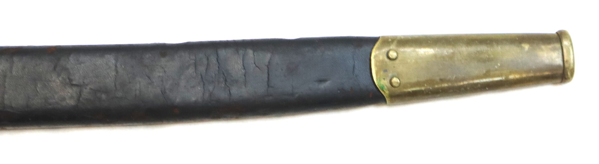 A close-up view of a worn black leather sword scabbard with a brass tip and rivets, set against a white background.
