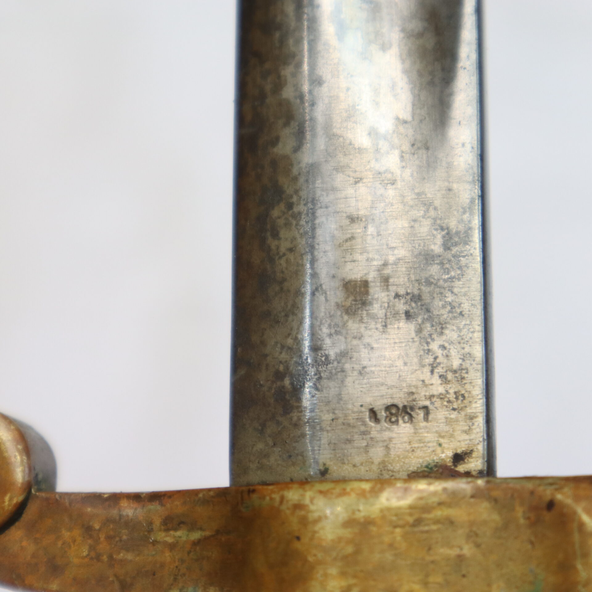 Close-up of a weathered metal blade with the number "1867" stamped near a brass hilt.