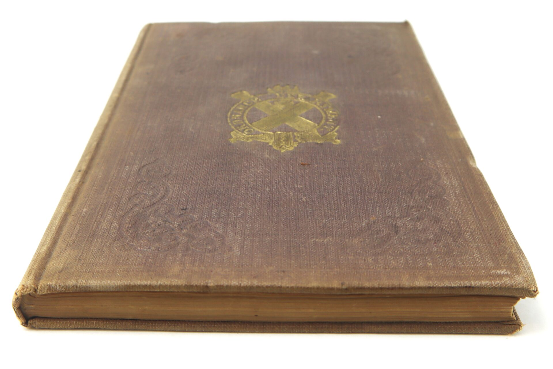 A closed, worn hardcover copy of the 1863 Ordnance Bureau Manual, identified to William A. Barker of the 4th Maine Volunteer Infantry, with a faded gold emblem on the cover, lies on a white surface.