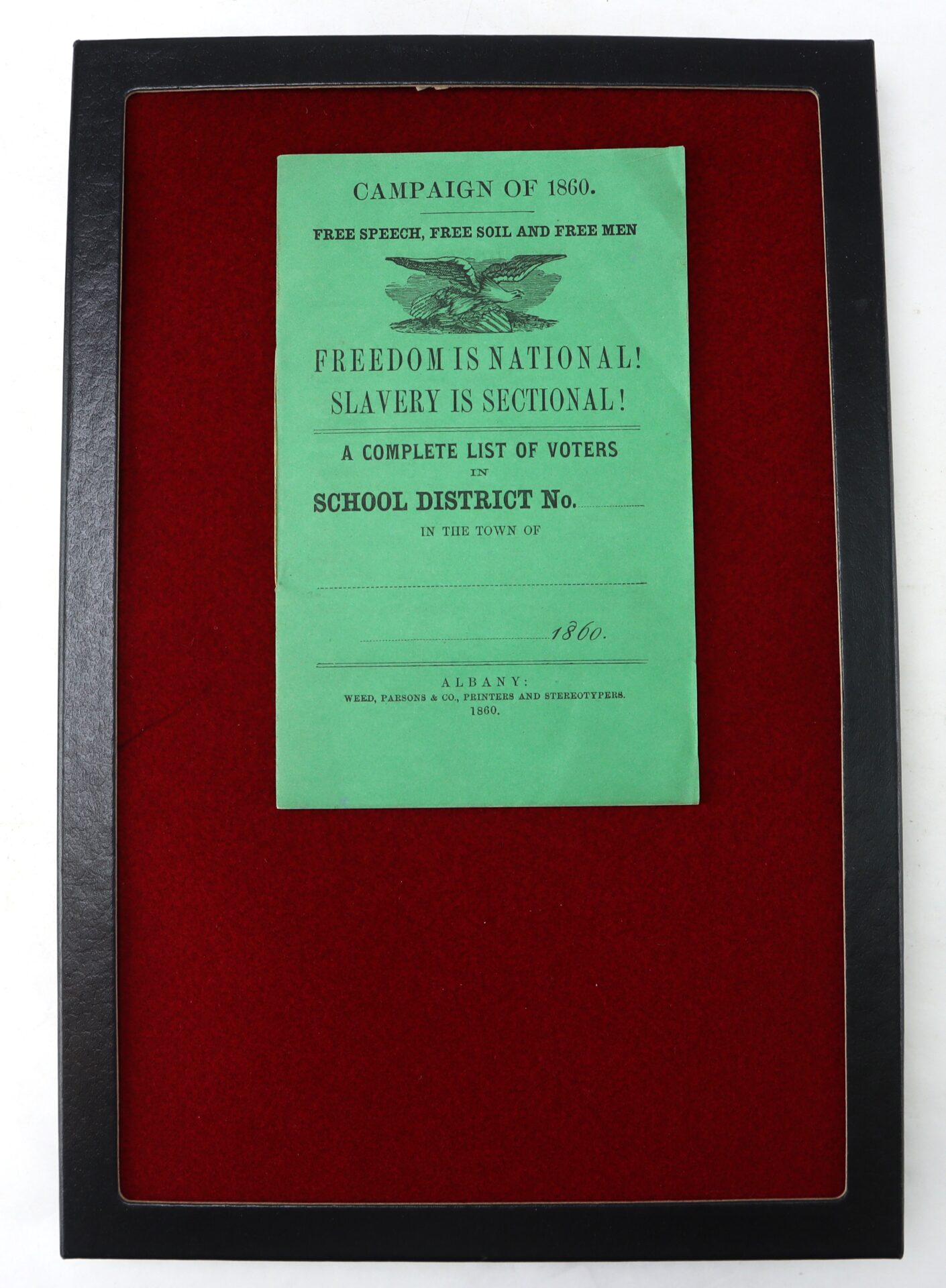 Framed campaign leaflet from 1860 with green paper advocating freedom and listing voters for a school district, displayed on a red background.