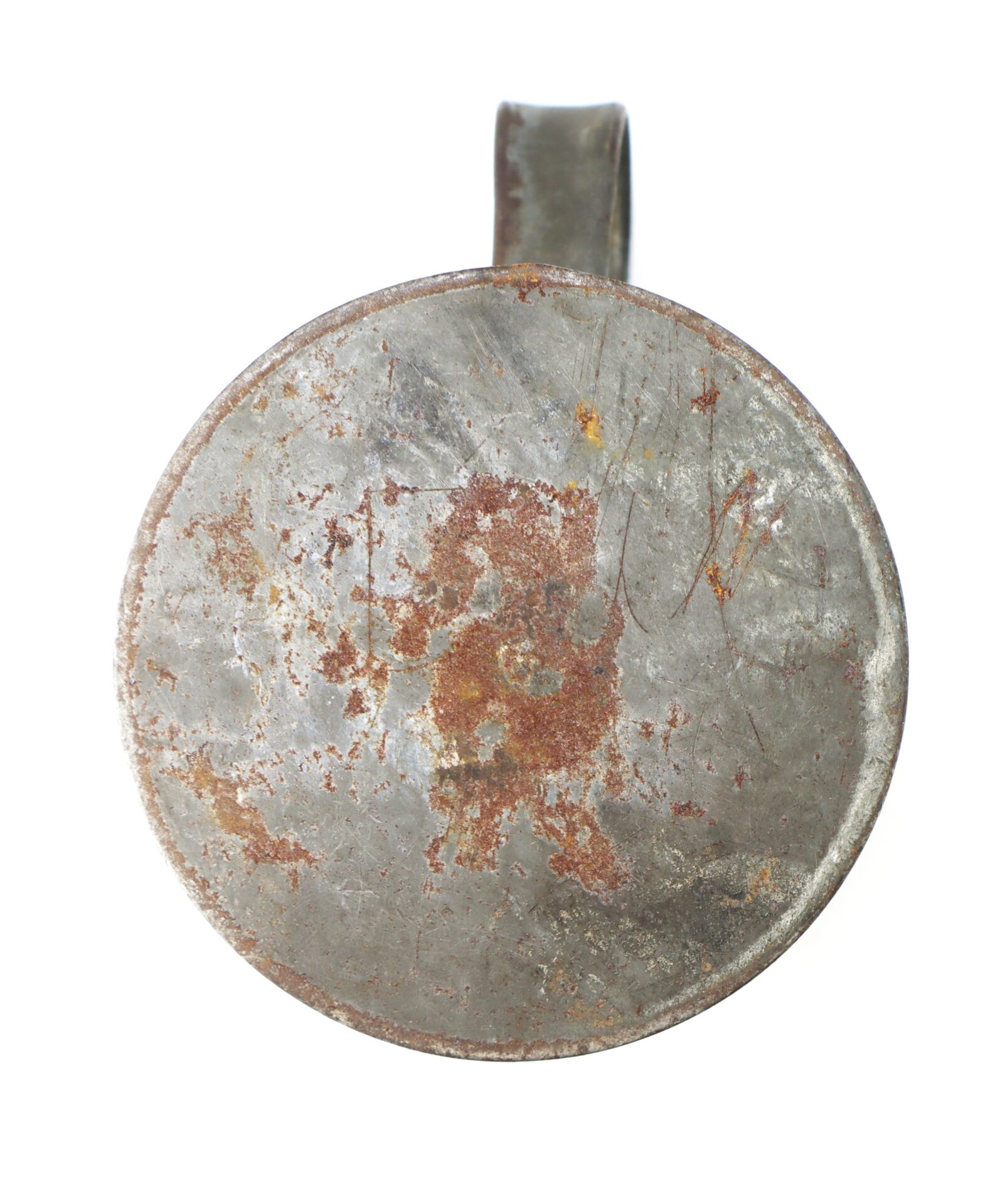 A top-down view of a round, weathered, and rusty metal object with a handle, possibly an old tin cup or container.