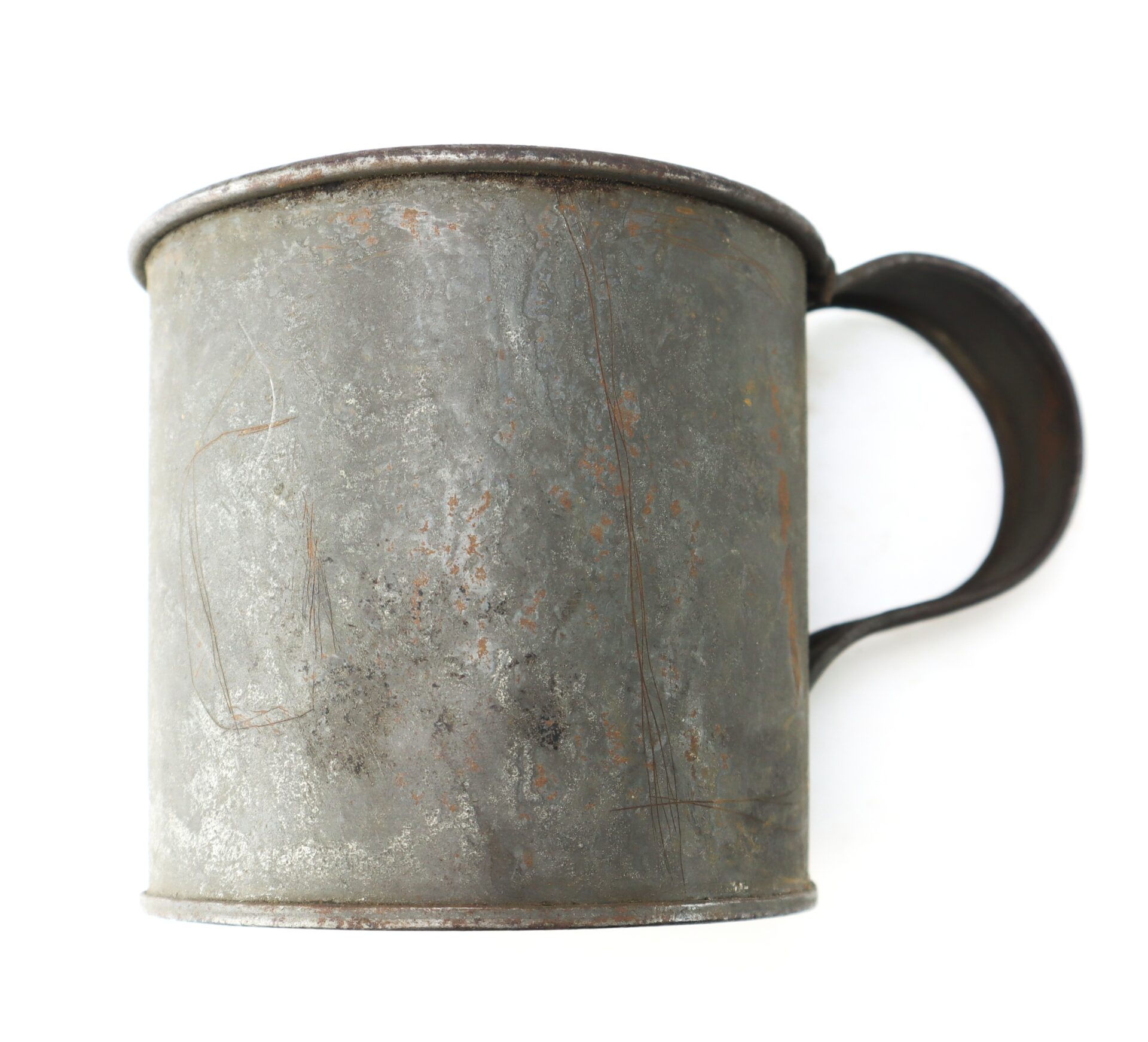 A weathered, metal mug with a large handle, showing signs of rust and surface scratches.