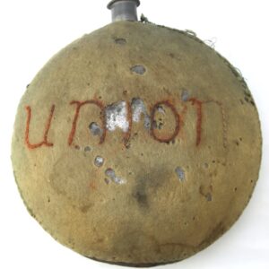 A worn, round canteen with a fabric cover embroidered with the word "Union" and showing signs of rust and damage.