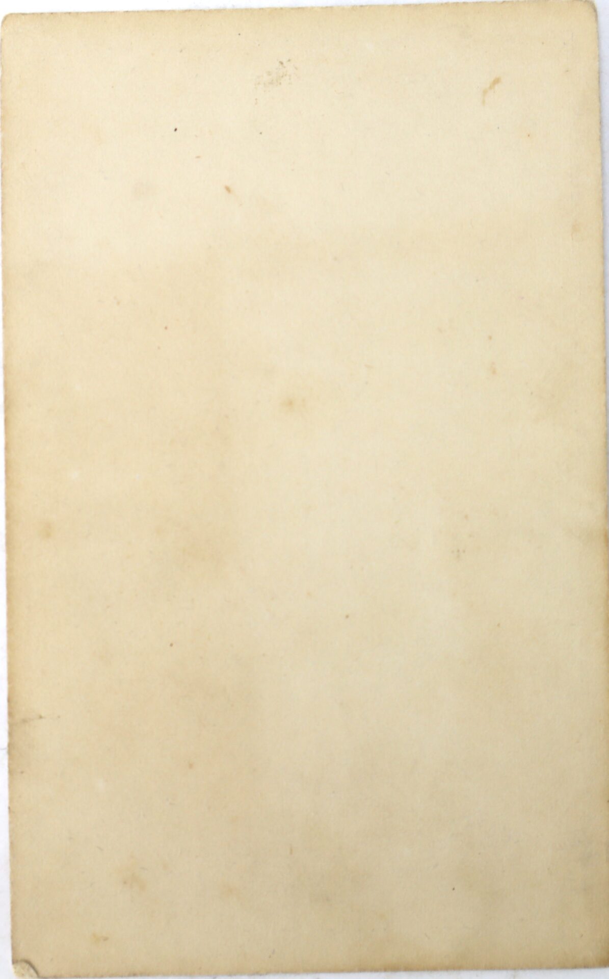 A blank, aged, and slightly stained sheet of paper with rounded corners and a few small marks.