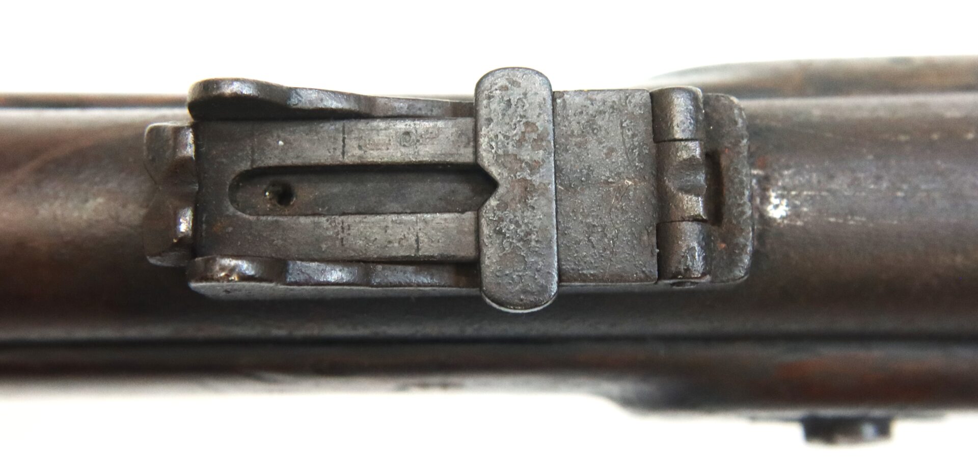 Close-up view of a metal gun sight mounted on a worn, rusted rifle barrel.