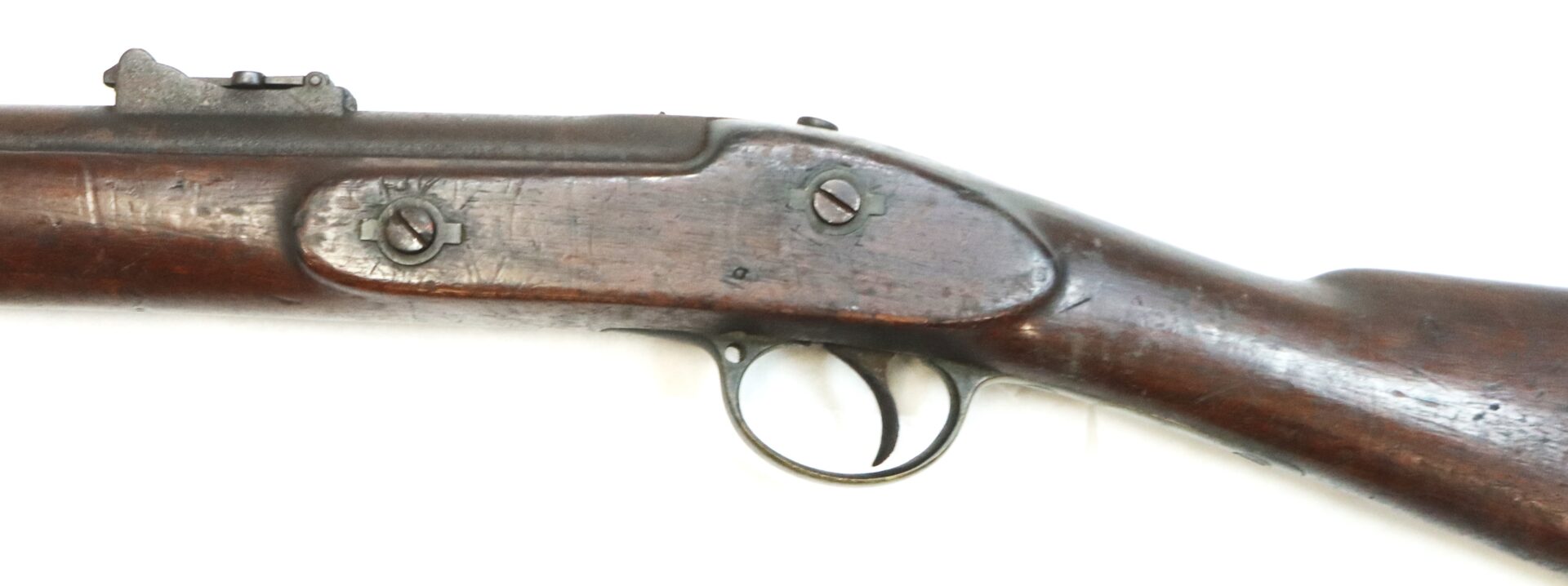 Close-up view of the wooden stock, trigger, and trigger guard of an old, vintage rifle against a white background.