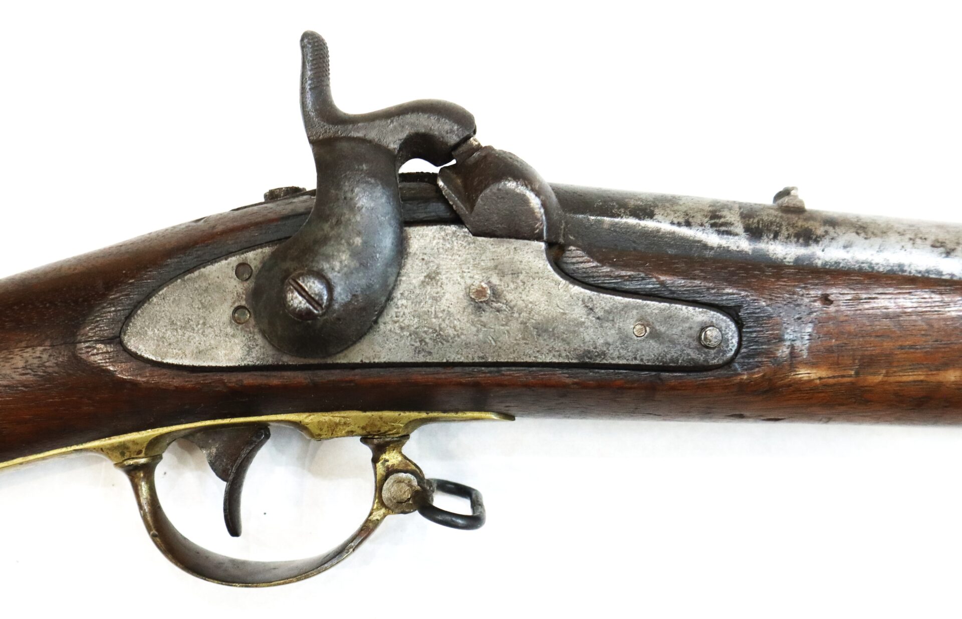 Close-up of an antique percussion cap rifle showing the lock mechanism, trigger, and part of the wooden stock.