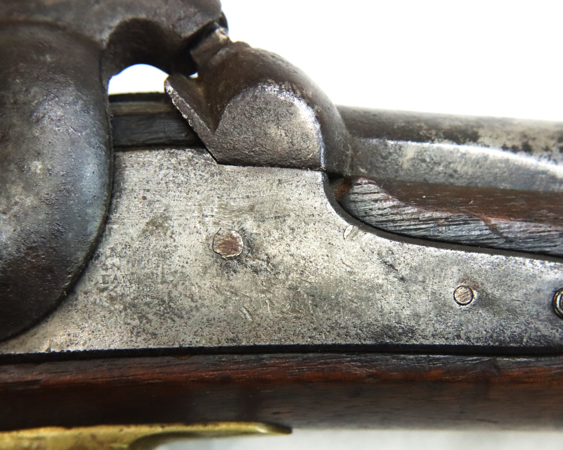 Close-up view of a metal and wood section of an antique firearm, showing the hammer and part of the lock mechanism.