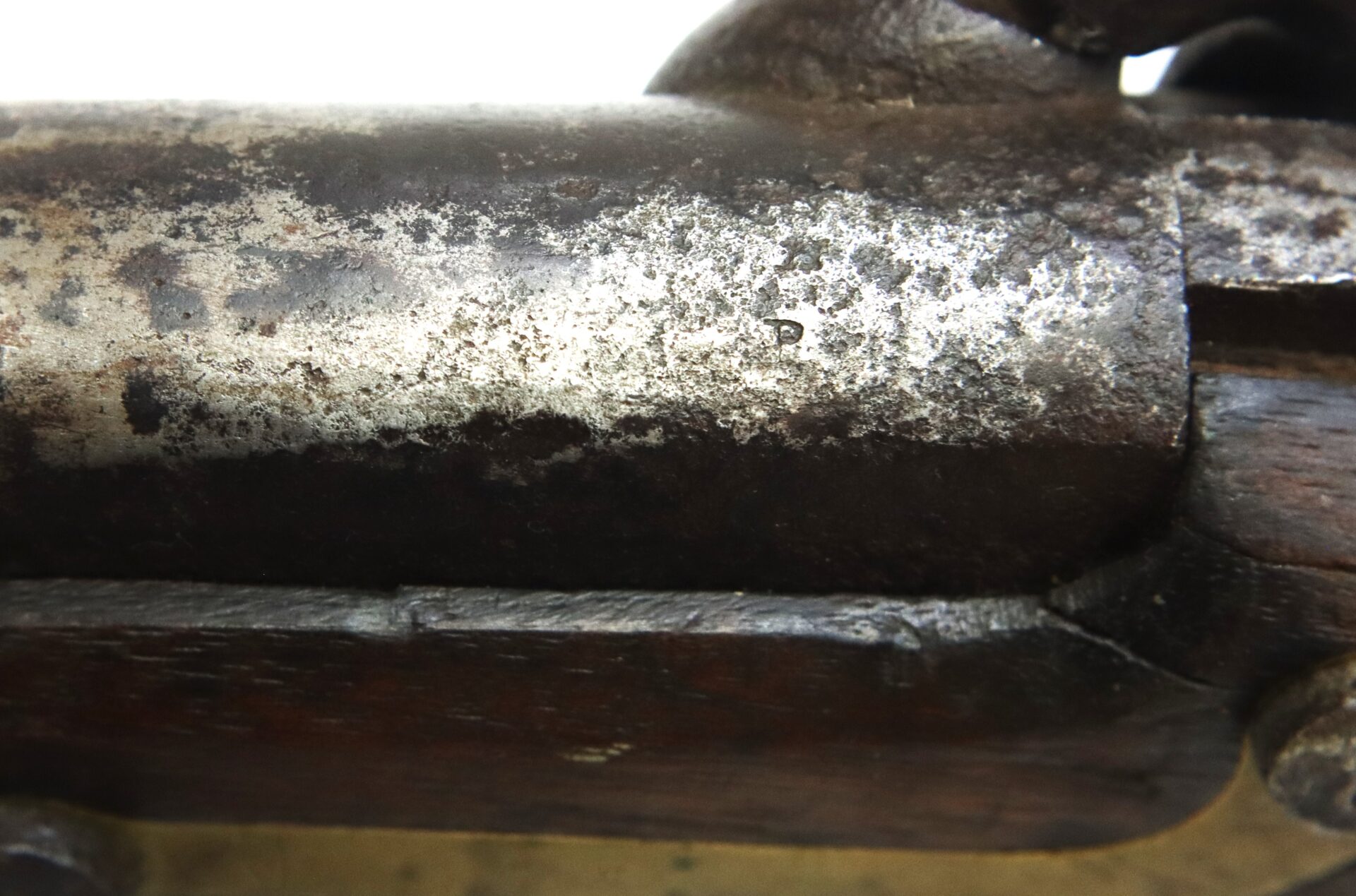 A close-up view of a rusted and worn metal surface, possibly part of an old firearm or mechanical tool, with visible corrosion and pitting.