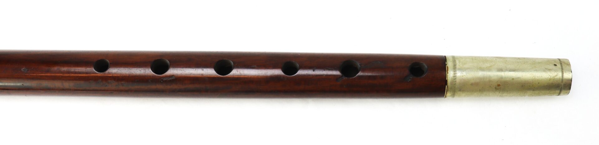 A wooden flute with six finger holes and a brass end, shown against a white background.