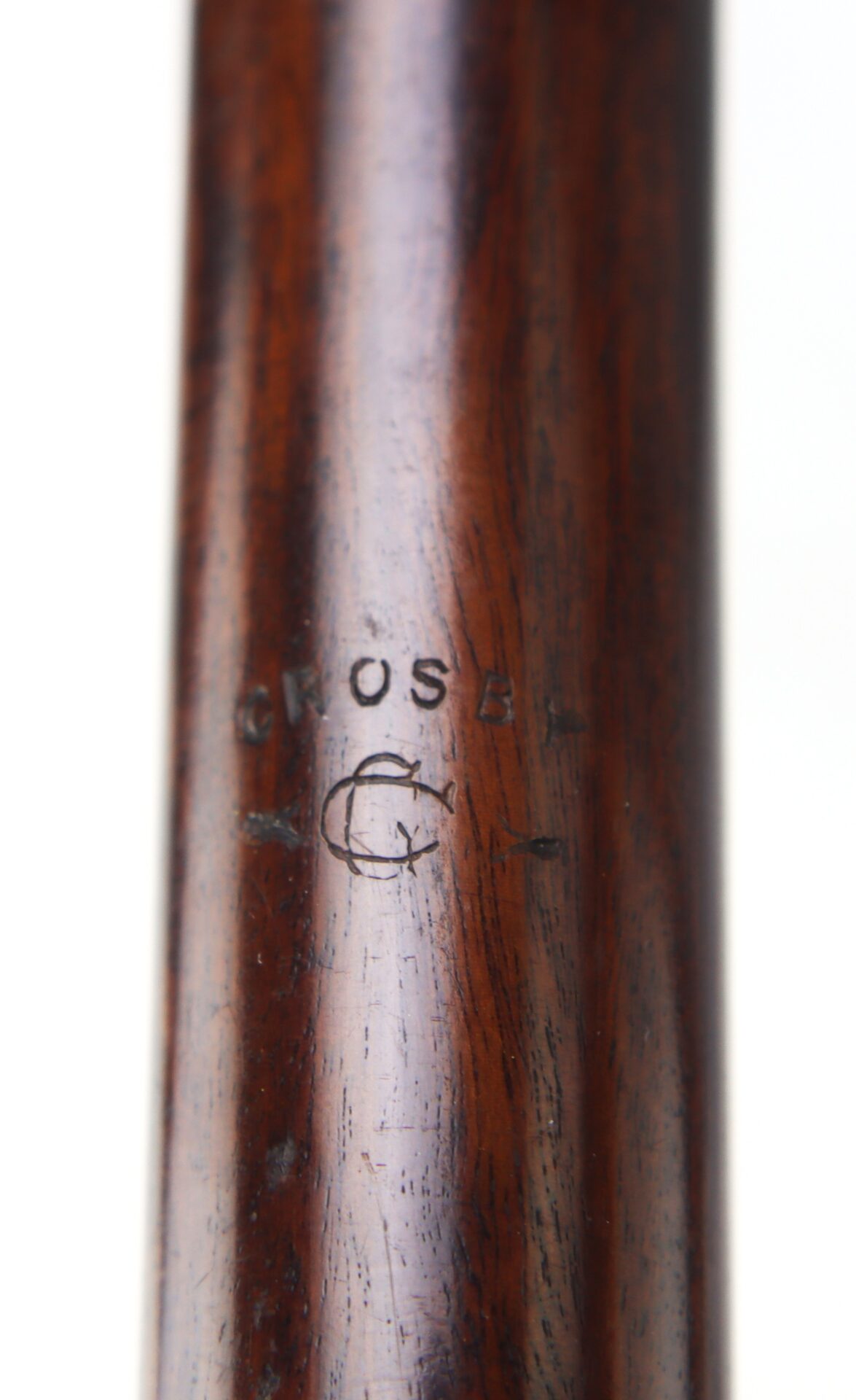 Close-up of a wooden surface with the word "CROSBY" and a stamped letter "G" visible on it.