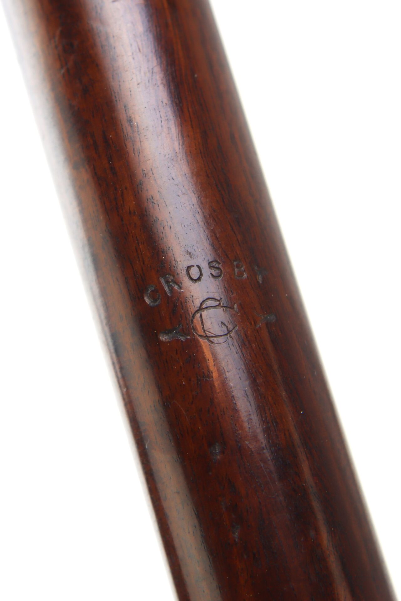 Close-up of a wooden object with the word "CROSBY" and a decorative symbol stamped into its surface.