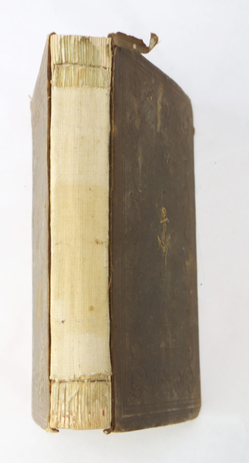 A worn, antique hardcover book with a damaged spine, faded cover, and an anchor symbol embossed on the front.