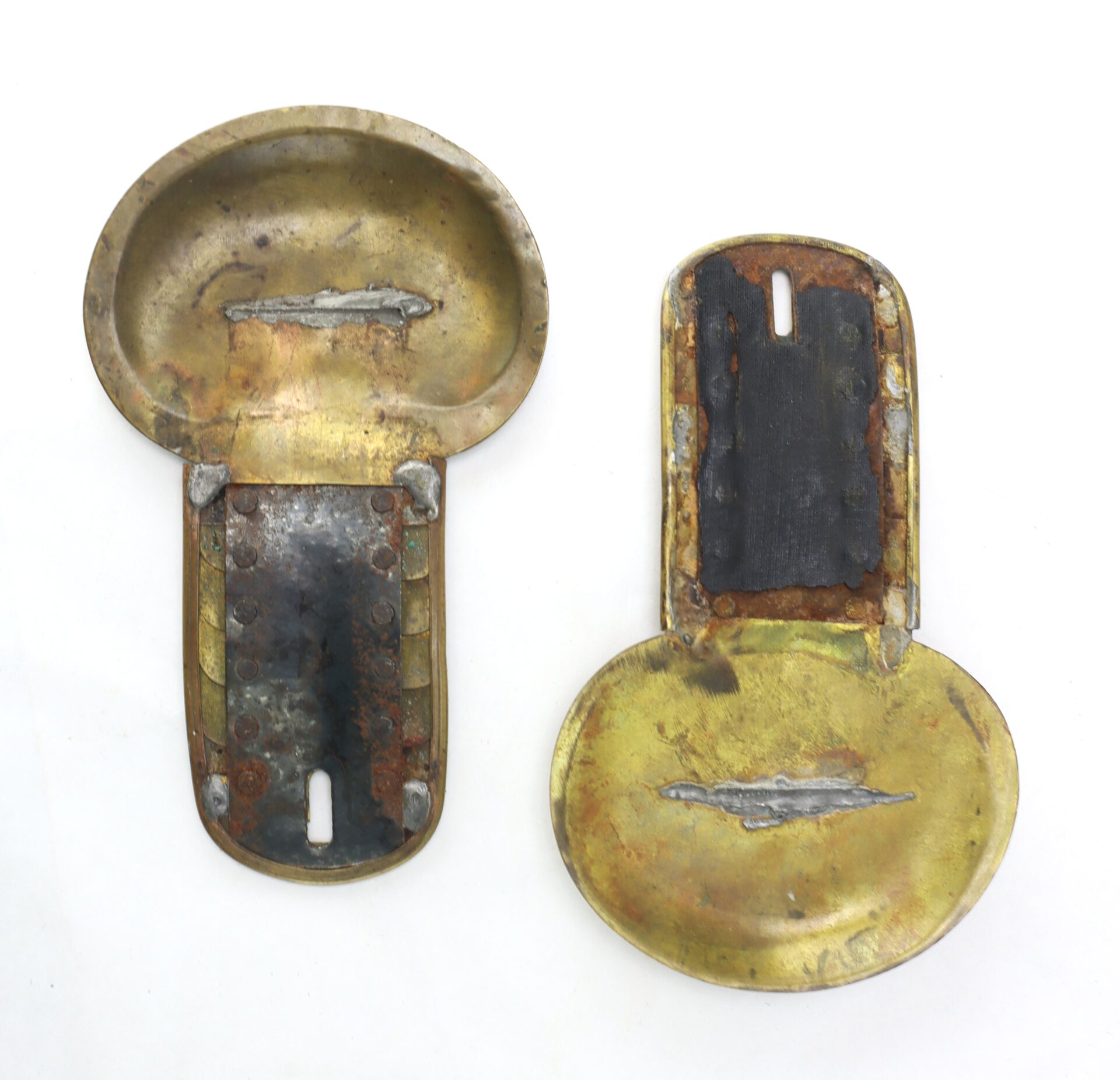 Two vintage brass belt buckles with visible rust and wear, shown opened to display interior and exterior surfaces on a white background.