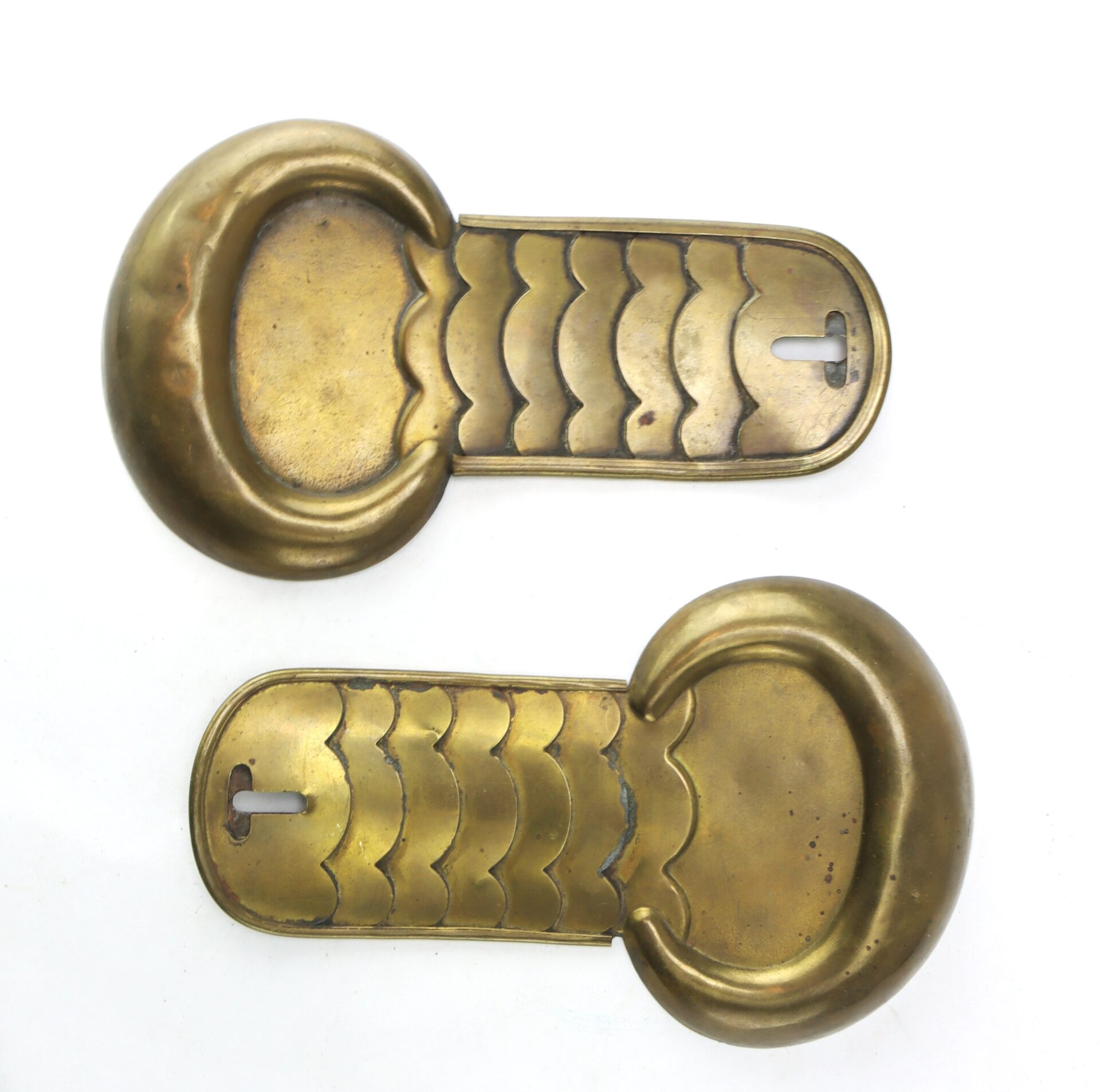 Two brass escutcheon plates with scalloped designs and keyhole openings, placed side by side on a white background.