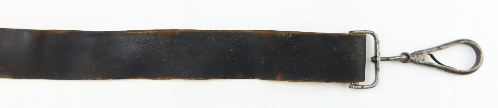 A worn, black leather strap with a metal clasp attached to one end, laid out flat on a white surface.