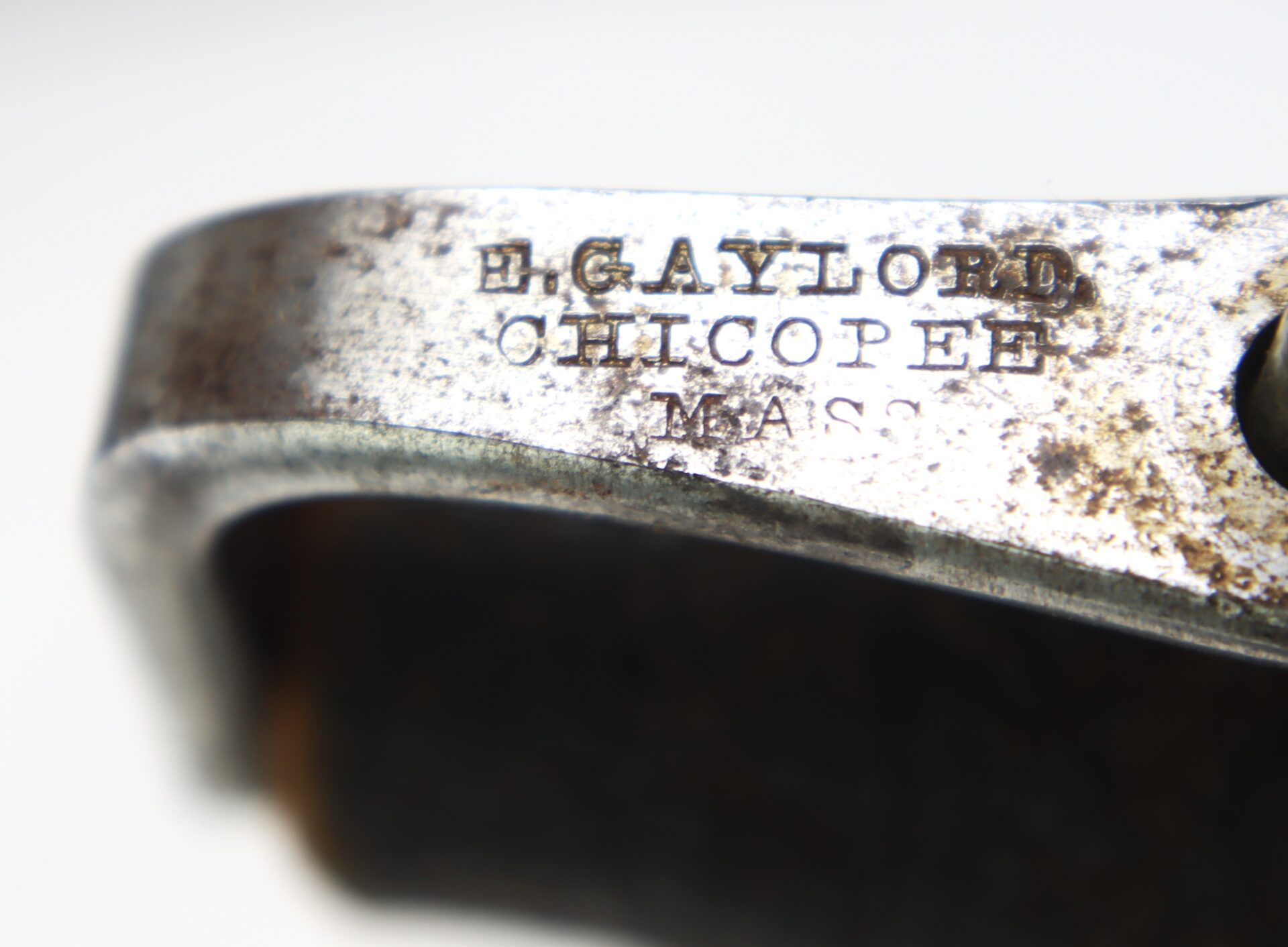 Close-up of a metal object engraved with the text: "H. Gaylord, Chicopee, Mass." The metal shows some rust and signs of wear.