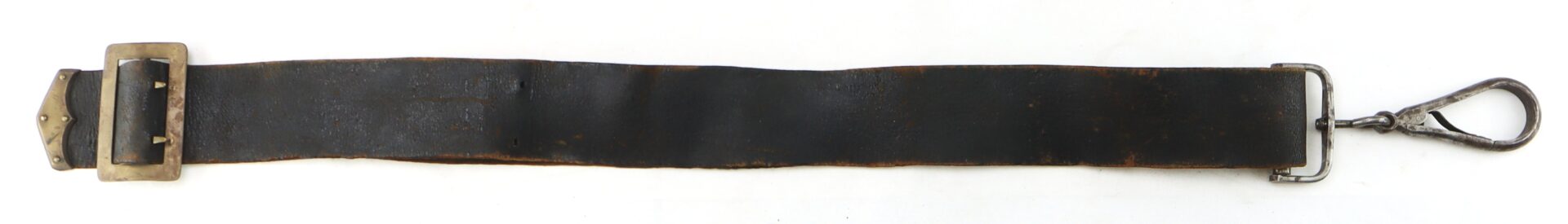 A worn black leather strap with a brass buckle on one end and a metal clip on the other, laid flat on a white background.